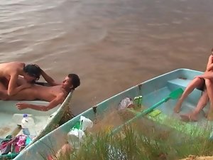 Sensual people are having group sex on the beach in a tiny boat